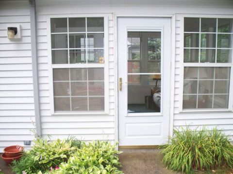 Storm door flanked by double hung windows - before