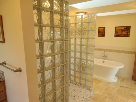 Larger completed bathroom remodel with walk in glass block shower and acrylic pedestal tub