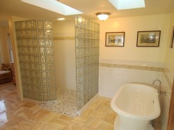 Glass block walk in shower with acrylic pedestal tub and white subway tile 