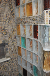 Inside curved and colored glass block shower with a tile row 