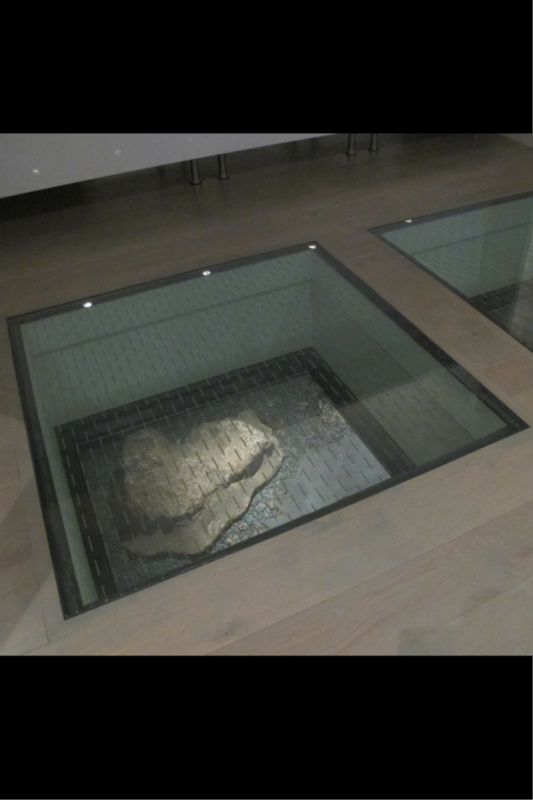 Looking down from a glass floor panel to a patio