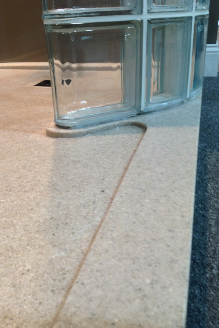 A cultured granite shower pan with a curved curb shaped for a walk in glass block shower | Innovate Building Solutions