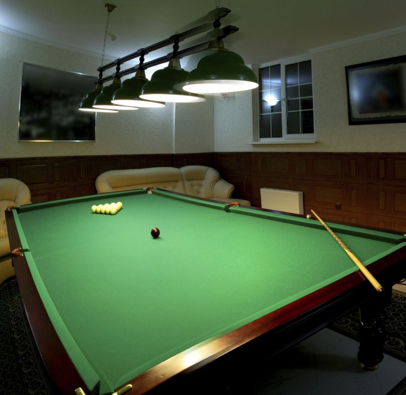 Pool table in a man cave with track lighting