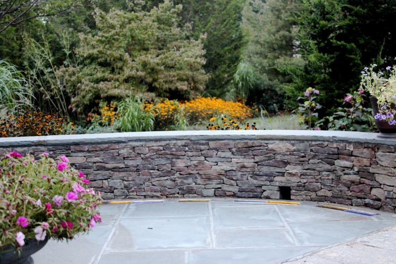 Curved stone retaining wall and colored glass pavers in a patio hardscape design in Guilford Connecticut 