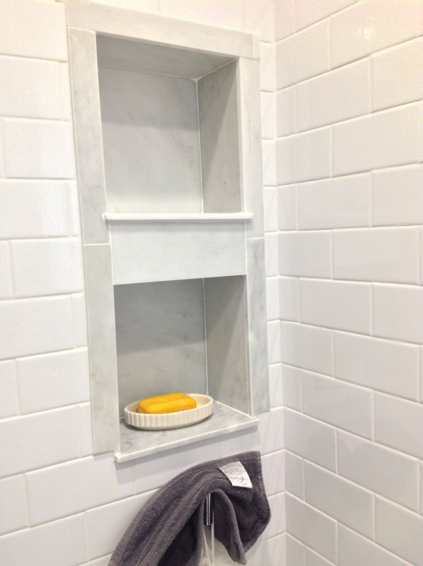 Recessed niche with Carrara marble around white subway tile ina shower