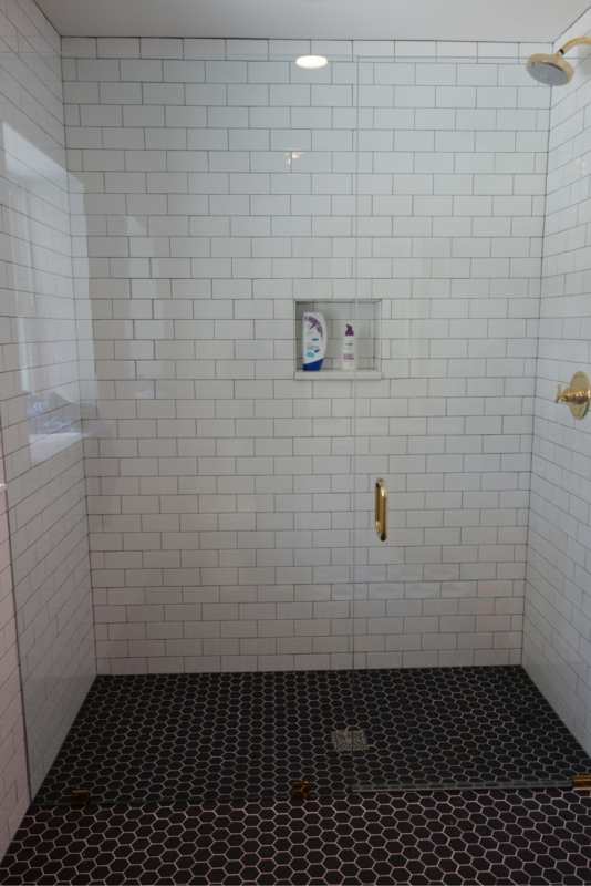 Roll in curbless shower with a frameless glass shower door. Using a shower screen which pivots inside and outside also makes a roll in shower warmer. | Innovate Building Solutions 