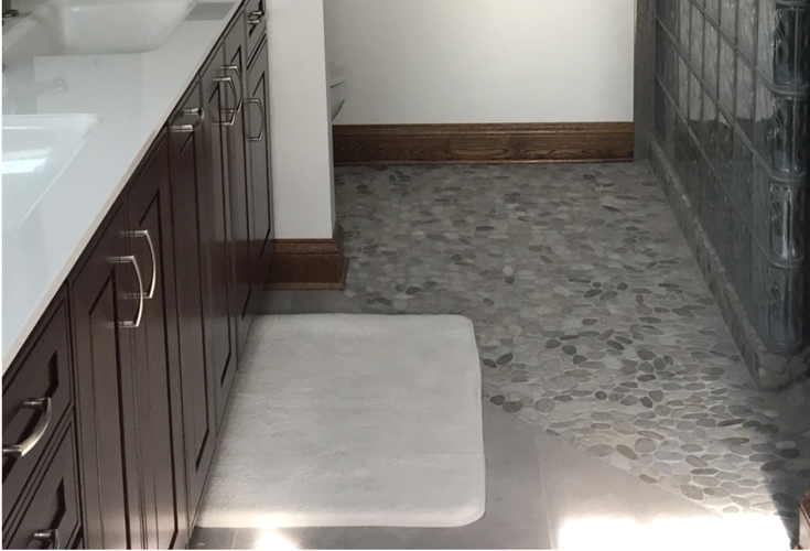 A curbless shower allows the pebble floor in the shower to spill out into the bathroom