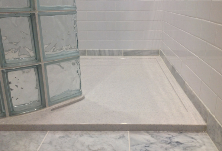 Low profile stone solid surface shower pan made for a glass block shower wall 