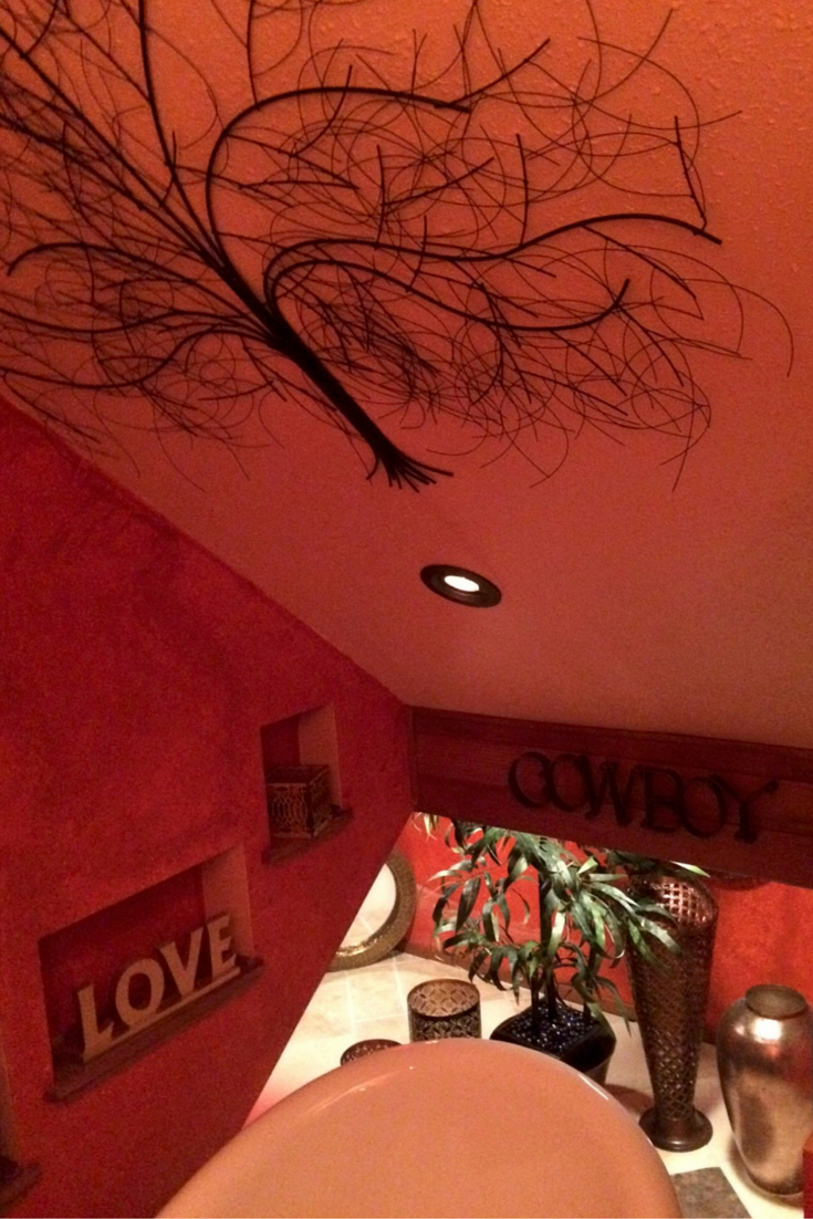 Artistic metal tree mural in a red colored bathroom in Santa Barbara California 