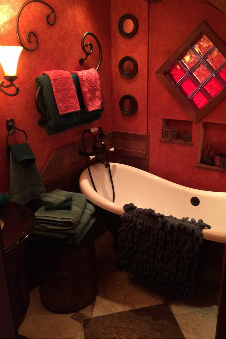 Custom remodeled bathroom with a clawfoot tub and red colored glass block window in Santa Barbara California