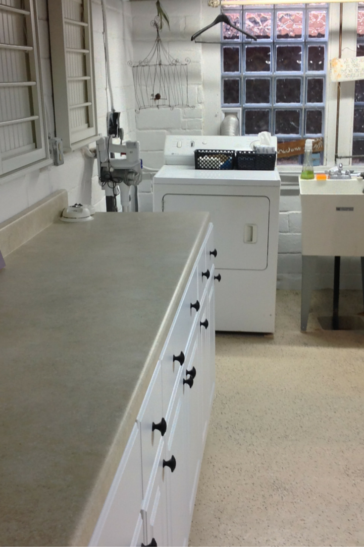 Finished laundry room with a long white counter and a large glass block window in university heights ohio