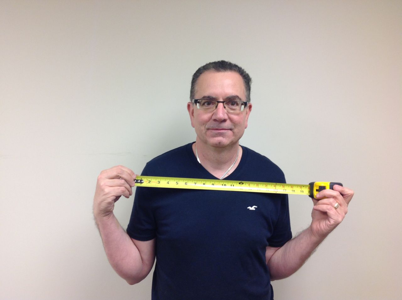 Mike Foti of Innovate Building Solutions measuring his personal width to determine the size of a shower opening 