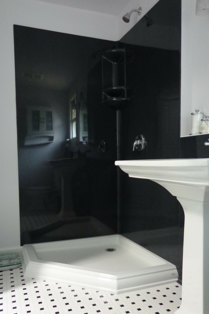 Black colored smooth solid surface shower wall panels in a corner shower - Innovate Building Solutions 