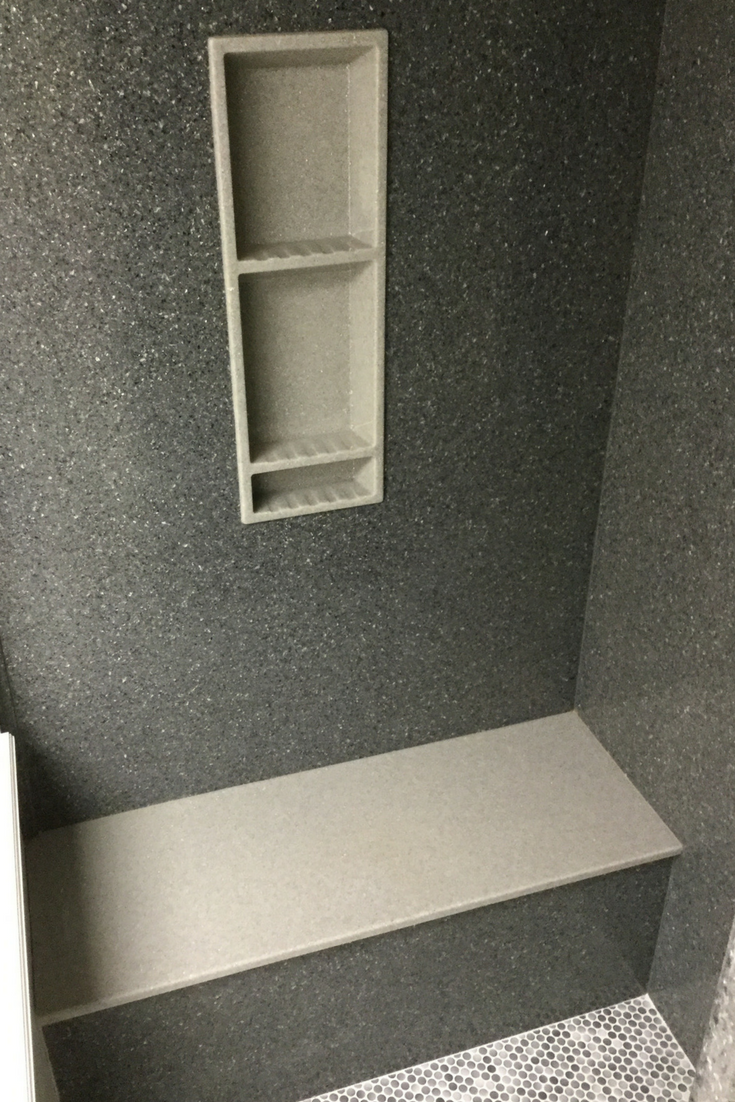 Solid surface slate texture shower walls with a different colored niche and bench seat | Innovate Building Solutions 