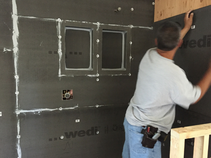 Wedi waterproof wall backer board panels being installed behind a tile shower | Innovate Building Solutions