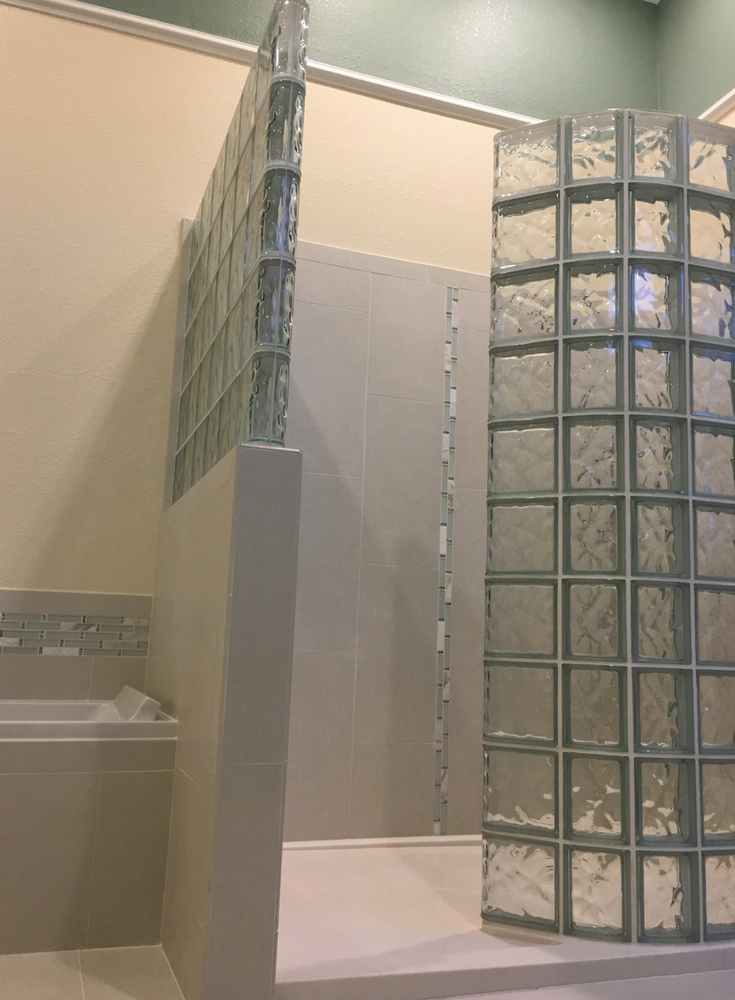 Custom shaped solid surface shower base with premanufactured glass block shower wall kit | Innovate Building Solutions