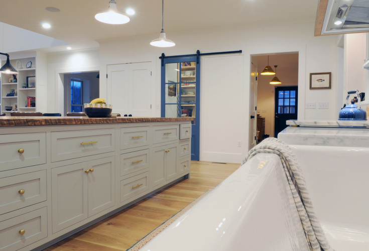 A sustainable modern farmhouse kitchen in Connecticut with a farmhouse sink, granite countertops and a sliding barn door leading into the pantry | Innovate Building Solutions 