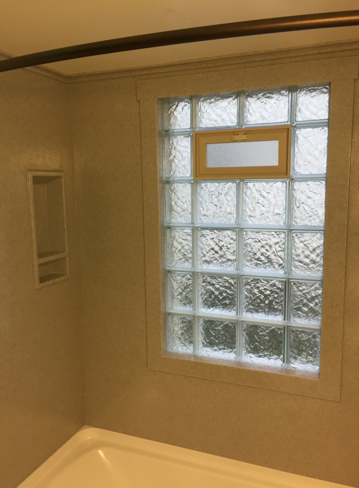 A glass block wave pattern vented window with solid surface trim for a watertight shower window | Innovate Building Solutions