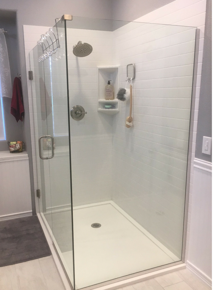 An easy to clean low curb solid surface shower floor pan in white with solid surface subway tile pattern grout free walls and a clear frameless glass enclosure | Innovate Building Solutions