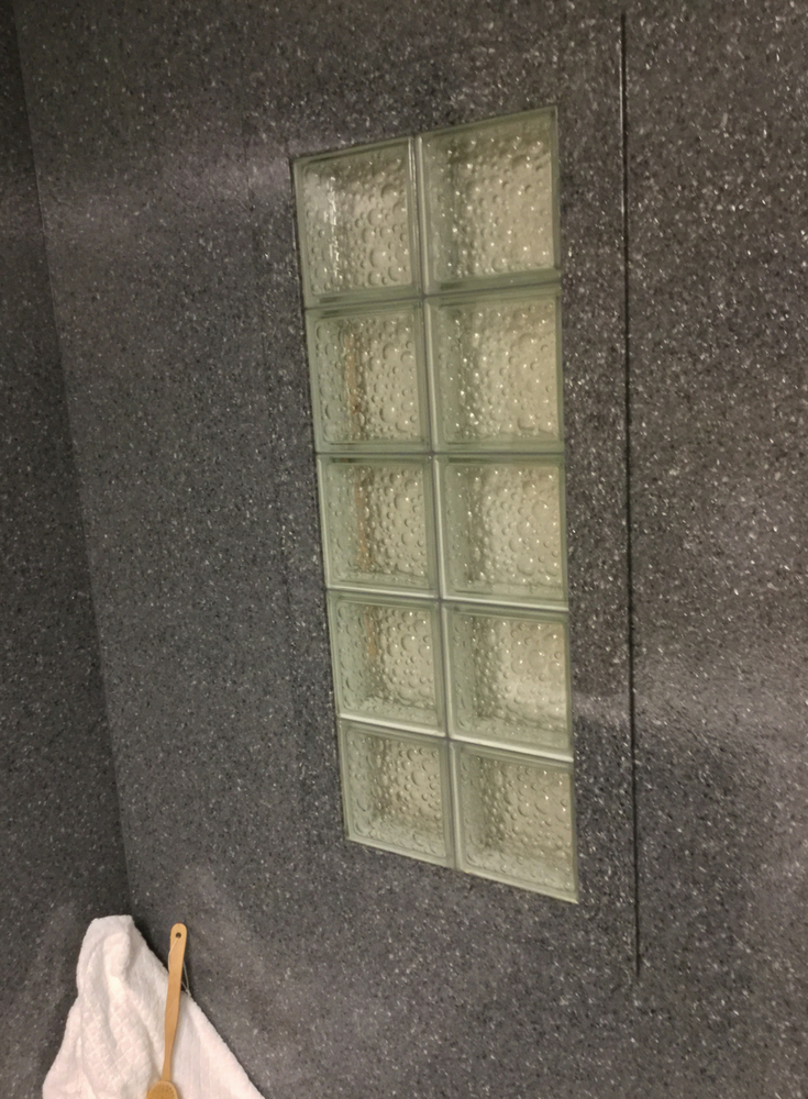 Darker colored solid surface window trim around a glass block window with a bubble pattern | Innovate Building Solutions 