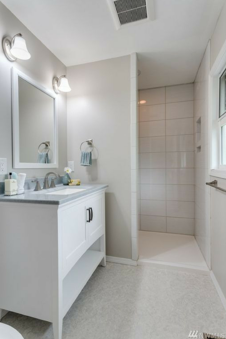 Low profile solid surface offset shower pan with a solid surface custom vanity top in a remodeled bathroom in California - Innovate Building Solutions