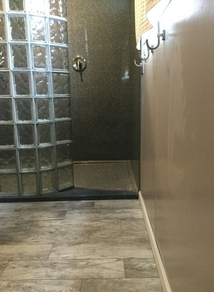 Stone solid surface custom low profile shower pan can be nice for an elderly Mom or Dad because it's easy to step over. The curved glass block walk in shower is sturdy and easy to maintain | Innovate Building Solutions 