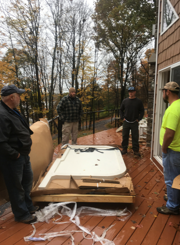 Solid surface custom shower pan is heavy and needs to be moved by these 4 guys - Innovate Building Solutions 