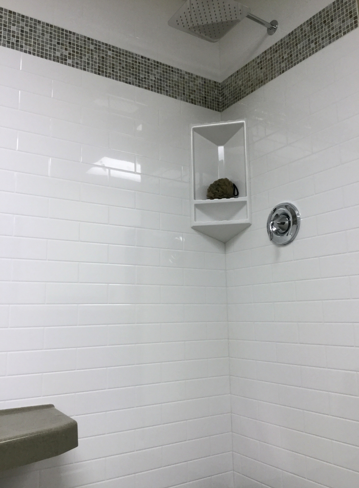 White subway tile pattern solid surface grout free shower panels with an iradescent glass tile row | Innovate Building Solutions