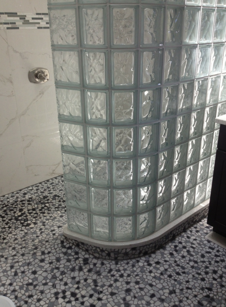 Curved glass block shower wall set on a ready for tile shower pan with a barrier free entry. | Innovate Building Solutions #GlassBlock #GlassBlockShower #ShowerRemodeling