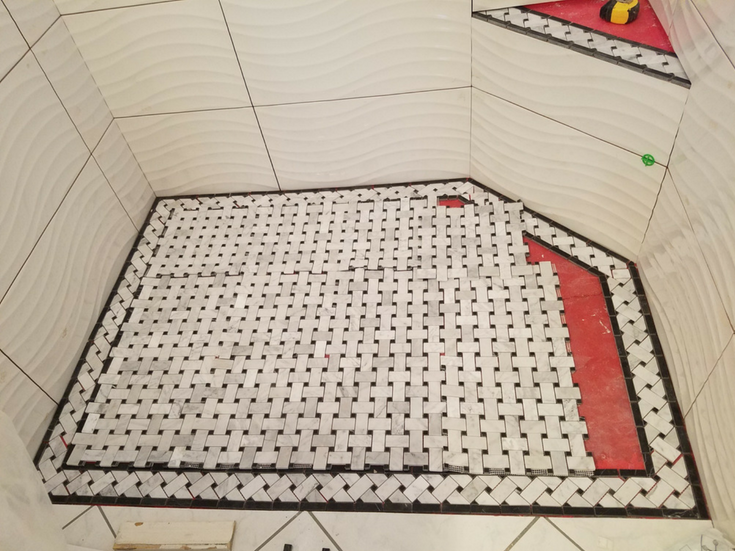 Basketweave tile pattern on a shower pan during installation | Innovate Building Solutions | #ShowerPan #TiledShowerBase #UniqueBathroom