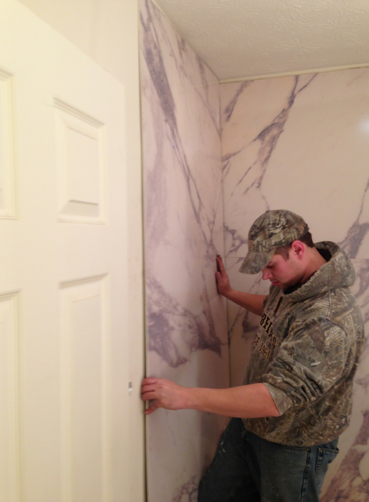 Faux marble PVC shower panels being installed on greenboard | Innovate Building Solutions | #FauxMarble #PVCShowerPanels #Greenboard #ShowerWallInstall