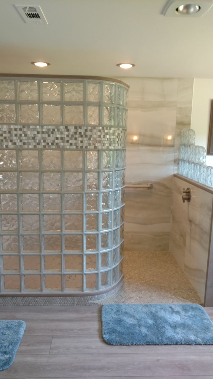 Glass block curved shower with a tile row | Innovate Building Solutions | #GlassBlockWall #ShowerWall #BathroomRemodel #GlassblockDesign