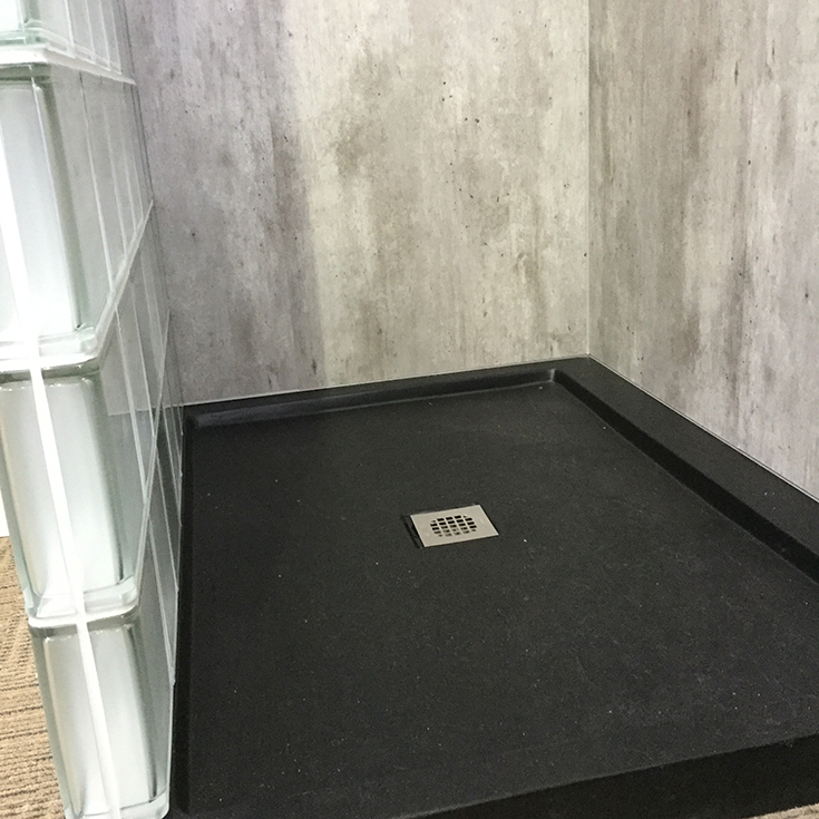 Matte black textured stone shower pan and cracked cement walls | Innovate Building Solutions | #MatteBlack #ShowerPan #TexturedShowerBase