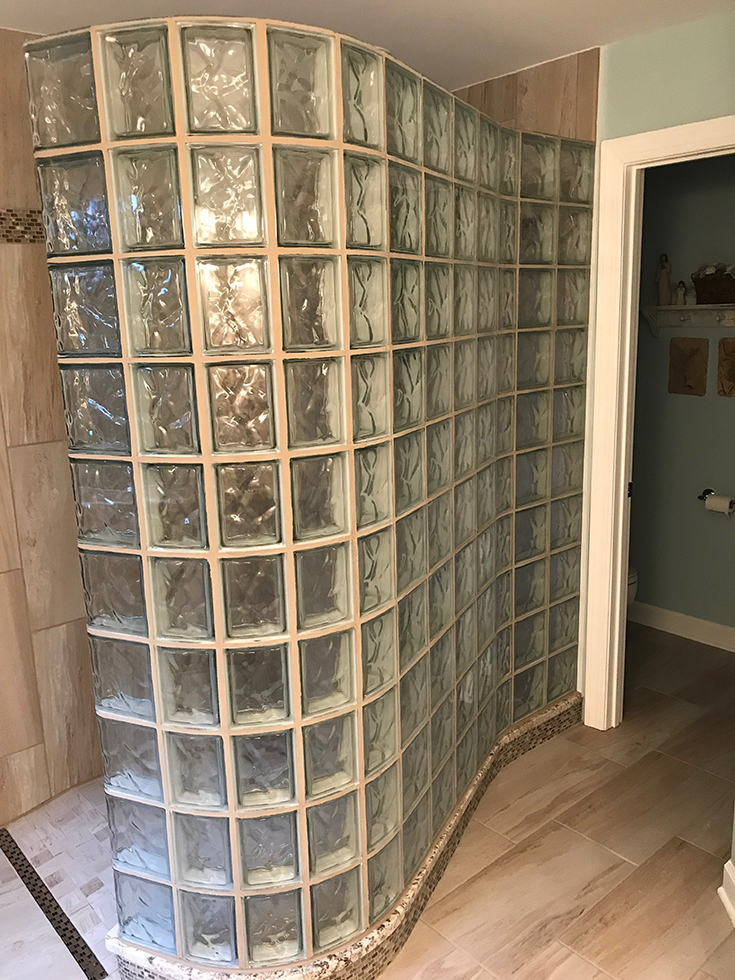 A serpentine glass block shower wall with a ready for tile base designed to fit it