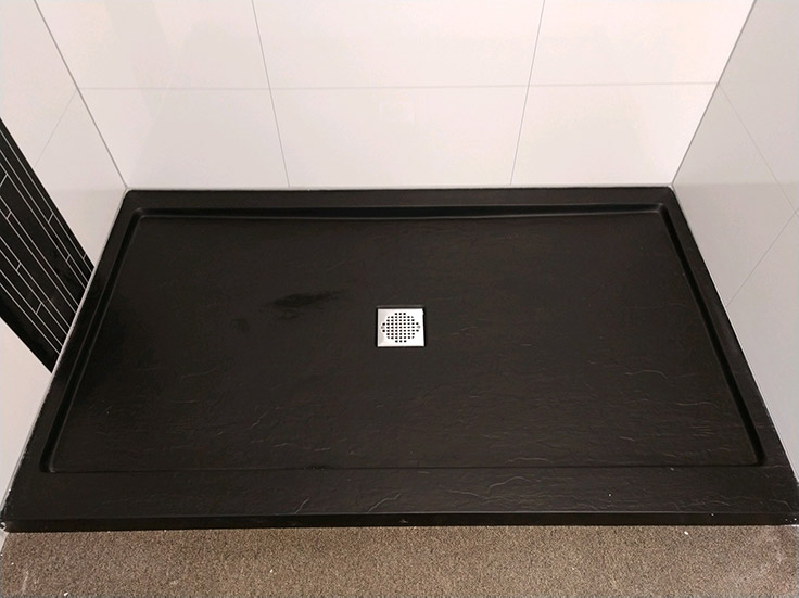 close up of cultured stone shower pan in matte black easy to clean | Innovate Building Solutions | #SolidSurface #ShowerPan #BlackShowerBase #MatteBlack