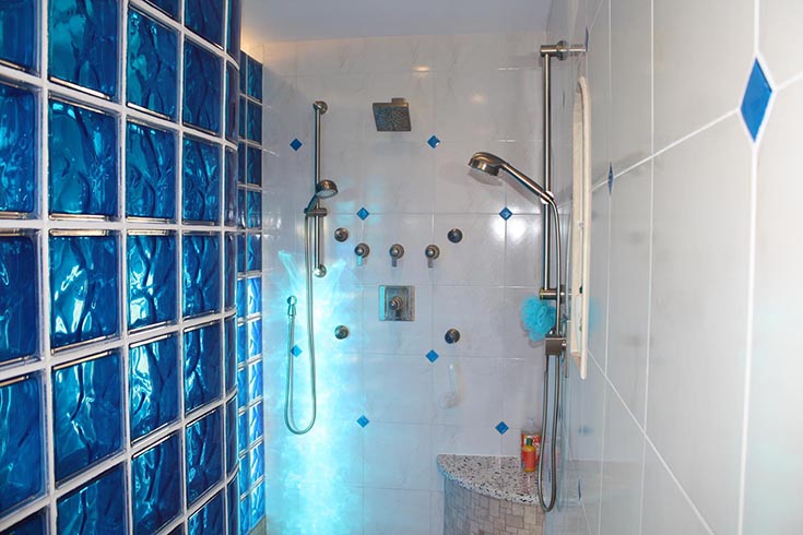 light shining through a colored glass block wall | Innovate Building Solutions | #Glassblockshower #Glassblockdesign #BathroomLight