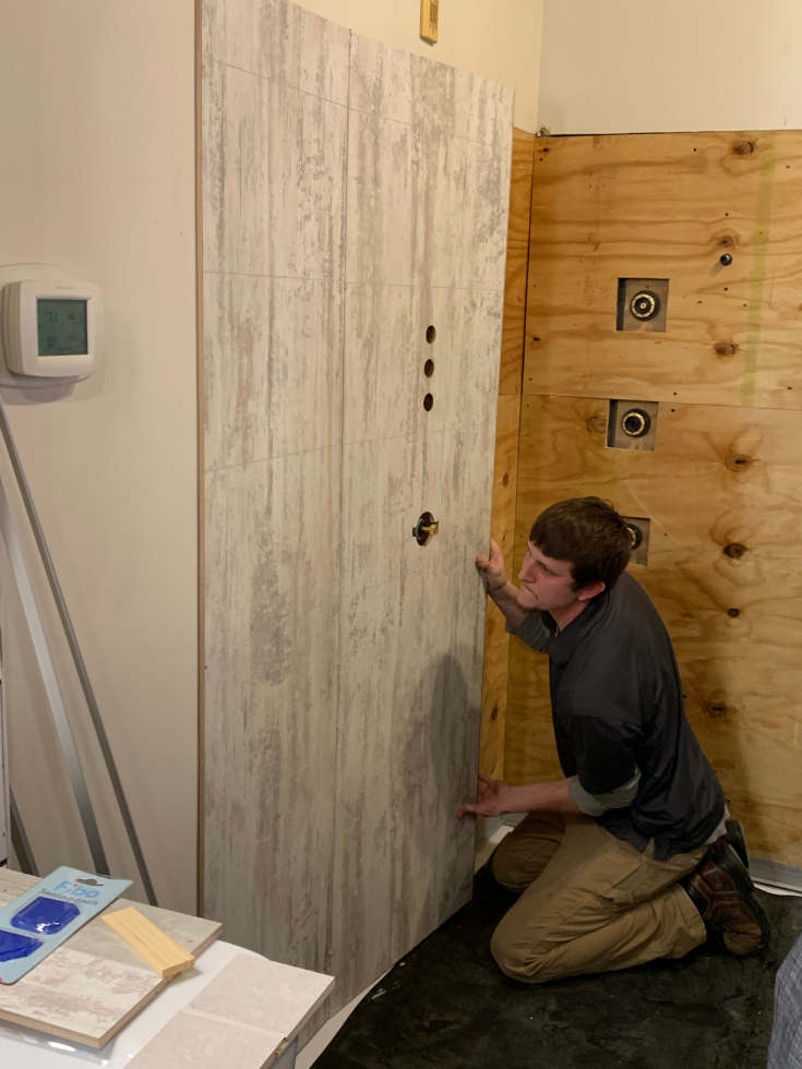 Step 4 click together laminate wall panels being installed with a white tile pattern | Innovate Building Solutions | #LaminateWallPanels #WhiteTile #WallPanels #BathroomRemodel