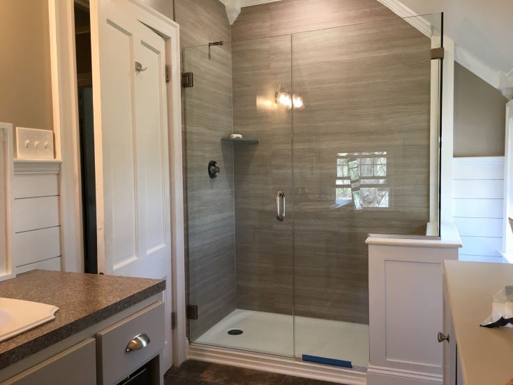 Factor 13 clear glass pivoting shower doors with laminate shower wall panels | Innovate Building Solutions #GlassSowerDoors #GlassShowerEnclosures #ShowerRemodel
