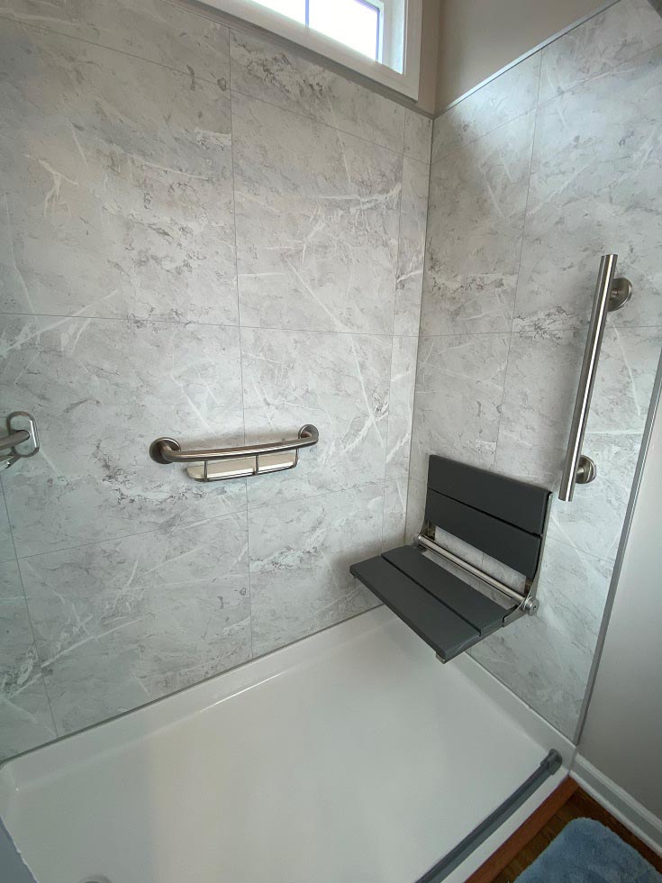 Step 9 fold down seat white marble shower wall surrounds accessible shower | Innovate building solutions | Glass block Shower Walls | Cleveland Bathroom remodel |Shower accessories for bathroom remodel